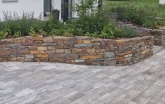 Gepflasterte Terrasse mit Natursteinmauer
